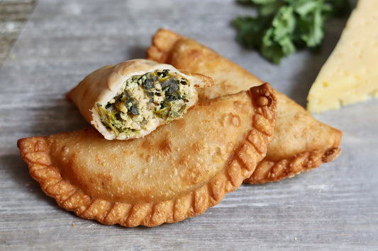 Spinach and Cheese Argentine empanadas ready to eat with a side of cheese and cilantro.
